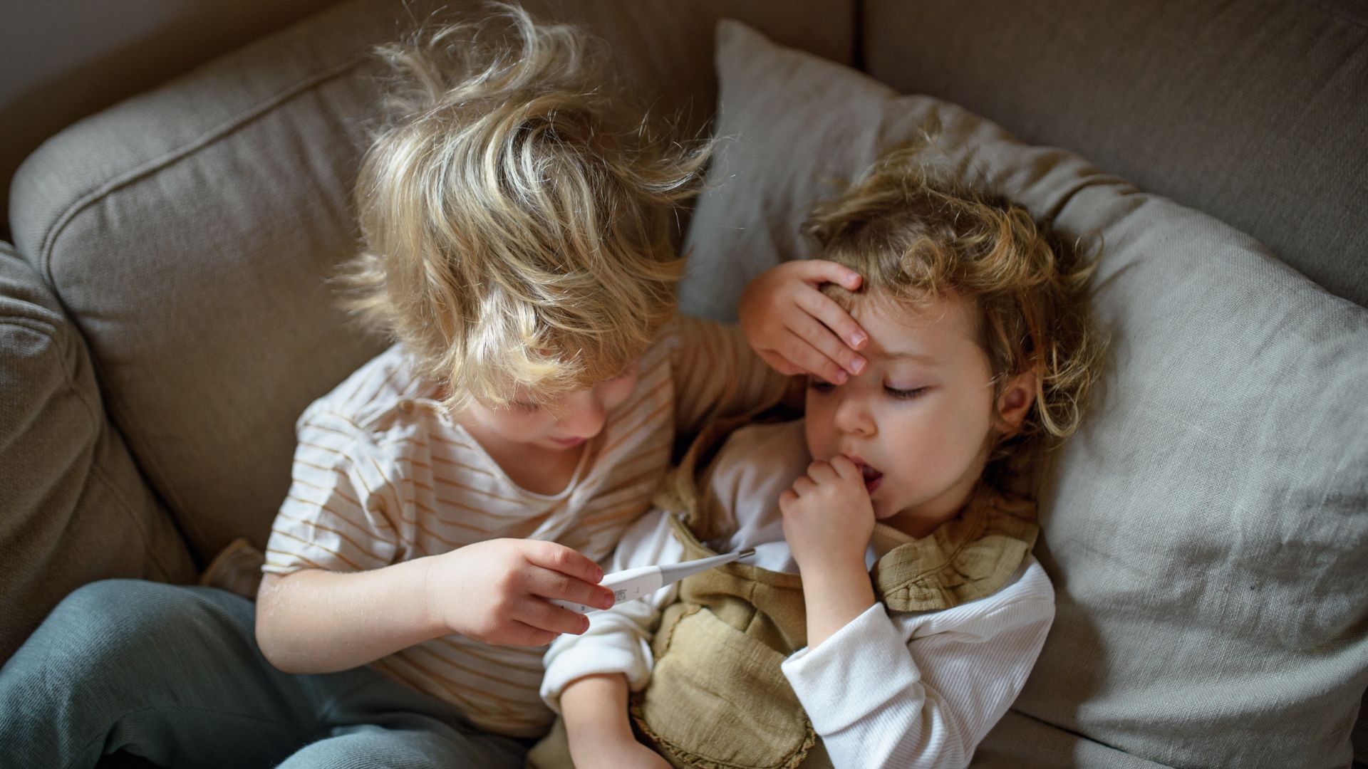Kinderkrankheiten: Unser Eltern-Leitfaden Zwei Kinder sitzen krank auf der Couch